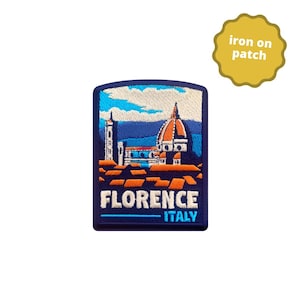 May include: Embroidered iron-on patch featuring a detailed illustration of Florence, Italy, with the Duomo and other buildings. The patch is rectangular with a navy blue border and the text "FLORENCE ITALY". A yellow scalloped tag reads "iron on patch".