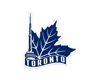 May include: A blue and white sticker with a stylized image of the CN Tower and a maple leaf with the word "TORONTO" on a banner.