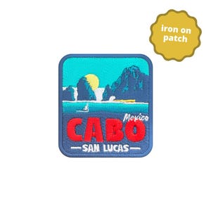 May include: Iron-on patch featuring a blue, green and yellow illustration of a beach scene with mountains and the text "Mexico CABO -SAN LUCAS-"