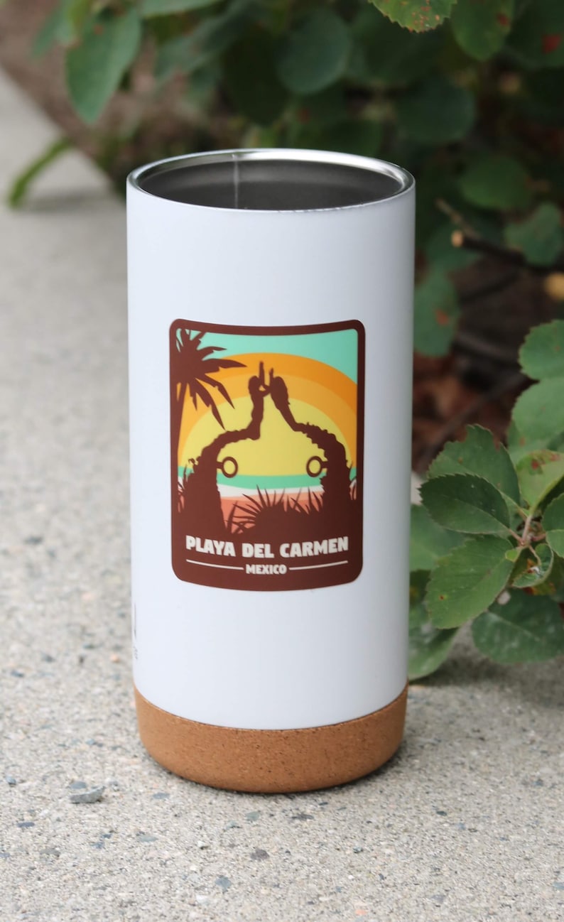 Pode incluir: Caneca de viagem branca com fundo de corti&ccedil;a. A caneca tem um gr&aacute;fico marrom de uma palmeira e um p&ocirc;r do sol com o texto "Playa del Carmen - M&eacute;xico".