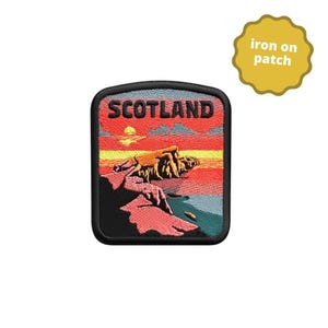 May include: A rectangular iron on patch featuring an embroidered landscape of Scotland. The design displays a sunset with red, orange, and yellow hues over rocky cliffs and a dark sea. The word SCOTLAND is stitched in black at the top.