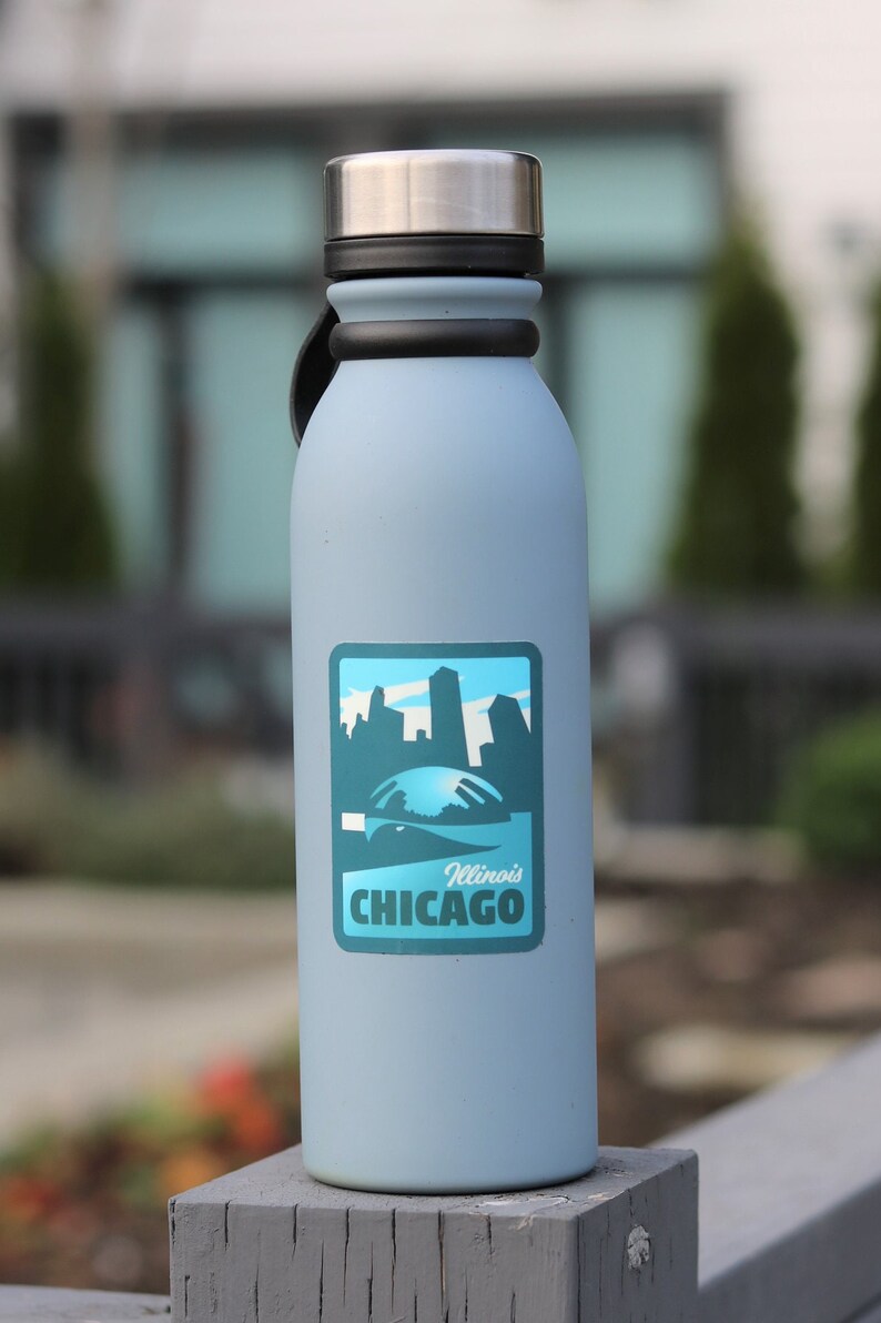 May include: A light blue water bottle with a black lid and a sticker featuring a skyline and the text "Illinois CHICAGO".