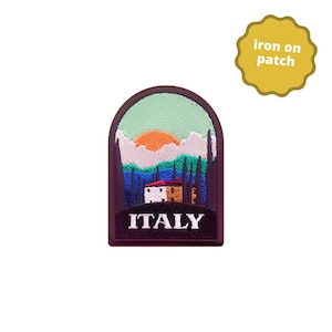 Peut inclure: Écusson brodé représentant un paysage italien avec un bâtiment blanc, des arbres et un coucher de soleil. L'écusson est bordé de violet foncé avec le mot "ITALY" en bas. Une étiquette jaune "iron on patch" est dans le coin supérieur droit.