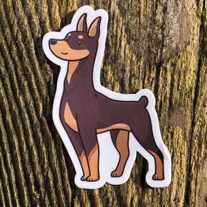 May include: A brown and tan cartoon sticker of a Doberman Pinscher dog standing on its hind legs.