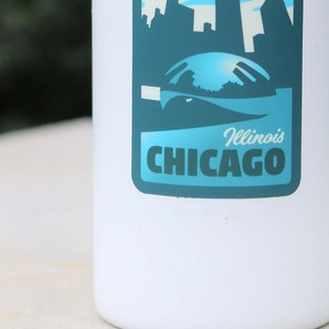 May include: White water bottle with a blue and green sticker featuring a skyline of Chicago, Illinois. The sticker says "Illinois CHICAGO" in white text.