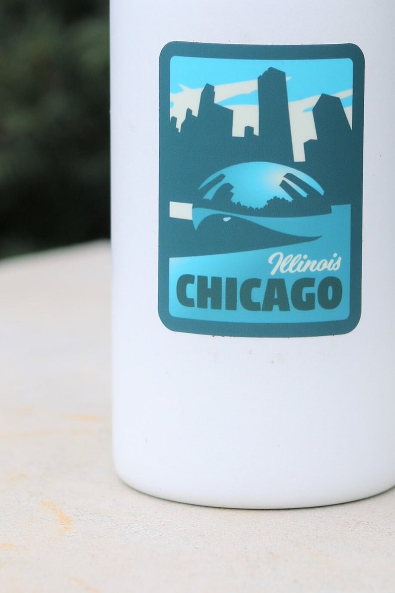 May include: White water bottle with a blue and green sticker featuring a skyline of Chicago, Illinois. The sticker says "Illinois CHICAGO" in white text.