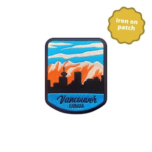May include: An iron-on patch featuring a scenic view of Vancouver, Canada. The design includes a black skyline, orange mountains, blue sky, and the city's name in cursive. The patch is bordered in blue.