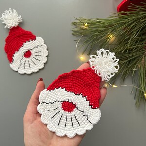 K&ouml;nnte beinhalten: Zwei geh&auml;kelte Weihnachtsm&uuml;tzen mit wei&szlig;en Bommeln. Die M&uuml;tzen sind rot und wei&szlig; mit einem wei&szlig;en H&auml;kelrand.