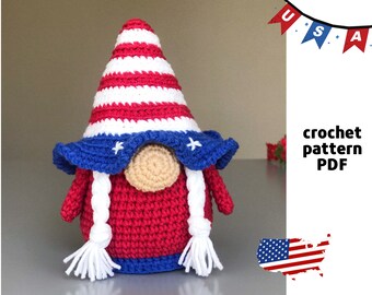 Puede incluir: Patrón de crochet PDF para un gnomo rojo, blanco y azul con un sombrero estrellado. El gnomo lleva un sombrero a rayas azul y blanco con un pompón blanco. El gnomo sostiene una pequeña bandera estadounidense.