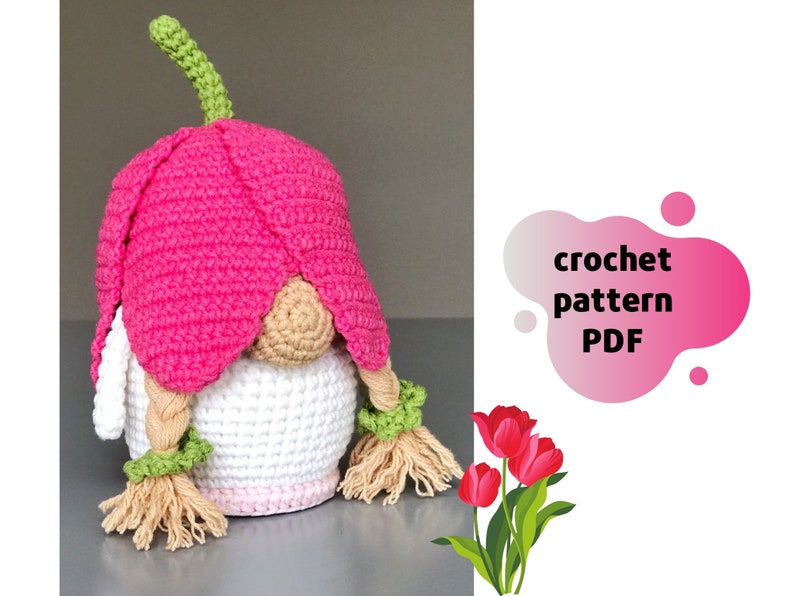 May include: Crochet pattern PDF for a pink and white gnome with a flower hat and braided hair. The gnome is sitting on a white surface. The text "crochet pattern PDF" is in a pink and white blob shape.