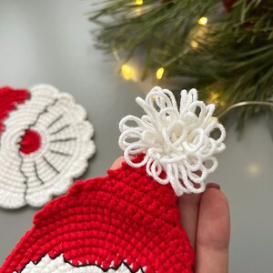 K&ouml;nnte beinhalten: Zwei geh&auml;kelte Weihnachtsm&uuml;tzen, eine rote mit einem wei&szlig;en Bommel und eine wei&szlig;e mit einem roten Bommel.