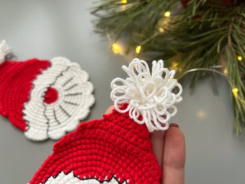 K&ouml;nnte beinhalten: Zwei geh&auml;kelte Weihnachtsm&uuml;tzen, eine rote mit einem wei&szlig;en Bommel und eine wei&szlig;e mit einem roten Bommel.