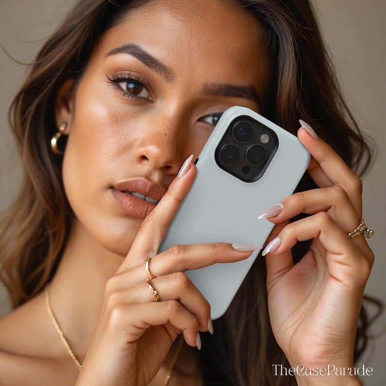 May include: A light grey smartphone case with a black camera module cutout. The case features a smooth, matte finish and is designed to fit a device with a triple-lens camera system. The text TheCaseParade is visible in the bottom right corner.