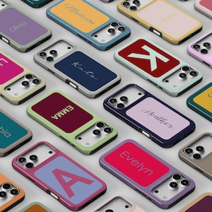 Puede incluir: Una colección de fundas rectangulares para teléfonos inteligentes con varias combinaciones de colores y texto personalizado. Cada funda tiene un panel central distintivo con nombres como Olivia, Madison, Angie, Kate, Emma, Heather y Evelyn, o letras grandes.