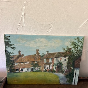 May include: Oil painting of a brick building with a green lawn and a pathway. The building has multiple windows and a brown roof. The sky is blue with white clouds. The painting is on a canvas.