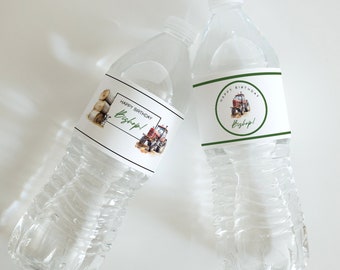 May include: Two clear plastic water bottles with personalized labels. The labels are white with green and black accents. One label features a tractor and hay bales with the text "Happy Birthday Bishop!" The other label features a tractor in a green circle with the text "Happy Birthday Bishop!"