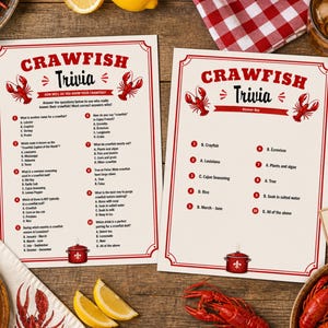 May include: Two cream-coloured Crawfish Trivia game sheets with red text and crawfish illustrations. The sheets are on a wooden table with food and drinks, including corn, lemons, and crawfish.