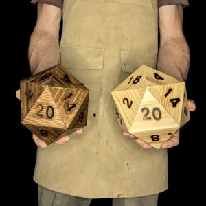 May include: Two large wooden twenty-sided dice, one with a dark wood stain and the other with a natural wood finish. The dice are numbered 1-20.