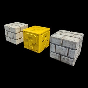 May include: Three toy blocks, two are grey and one is yellow. The yellow block has a question mark on it.