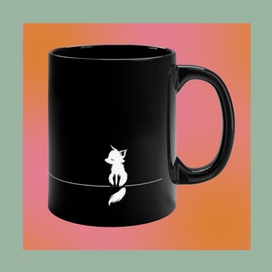 May include: Black ceramic mug with a white illustration of a fox sitting on a line. The fox is facing left with its eyes closed. The mug has a large handle and a glossy finish.