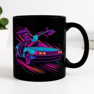 Op de afbeelding: Zwarte keramische mok met een kleurrijke illustratie van een retro auto met vleugeldeuren. De auto is afgebeeld in blauwe, roze en paarse tinten tegen een zwarte achtergrond, met kleurstrepen die beweging suggereren.