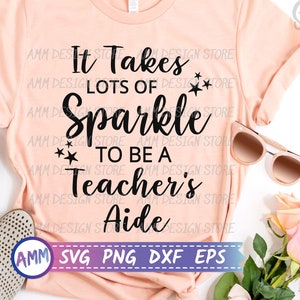 Puede incluir: Una camiseta rosa con el texto "It Takes Lots of Sparkle to Be a Teacher's Aide" en letras negras. La camiseta está puesta plana sobre una superficie blanca con unas gafas de sol y un ramo de rosas rosas.
