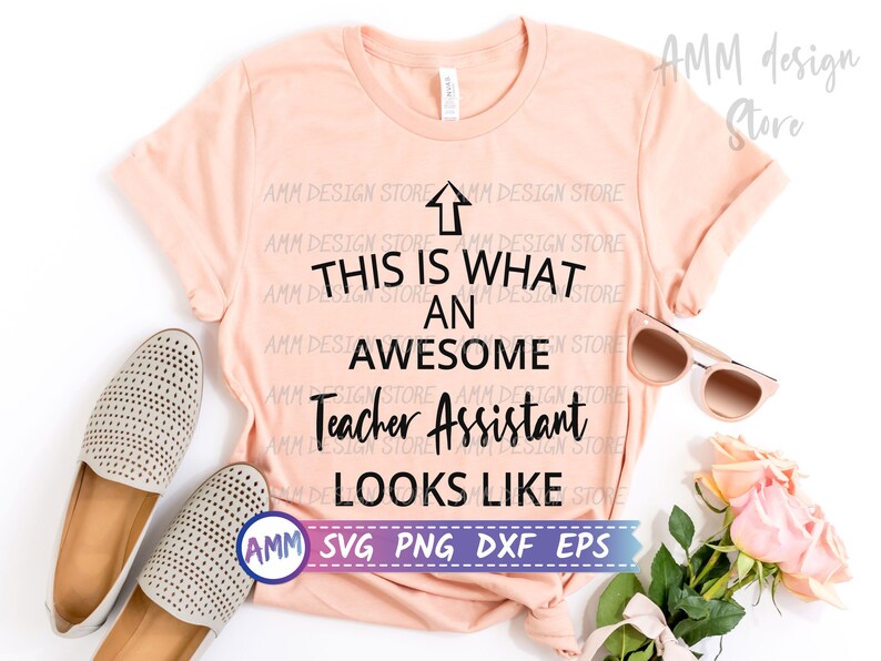 May include: A pink t-shirt with the text "This is what an awesome Teacher Assistant looks like" in black lettering. The text is centred on the shirt. The shirt is lying flat on a white surface with a pair of beige shoes and a pair of sunglasses.