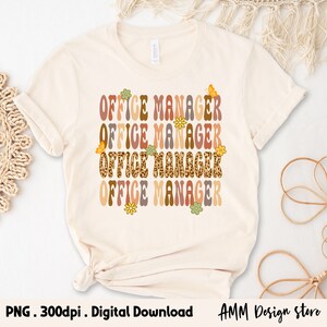 Pode incluir: Uma camiseta bege com o texto "OFFICE MANAGER" repetido quatro vezes em uma fonte retr&ocirc;. Cada palavra est&aacute; em uma cor diferente e tem um design floral ou de borboleta.