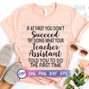 May include: A peach-coloured t-shirt with the text "If at first you don't succeed try doing what your teacher assistant told you to do the first time" in black text. The text is centred on the shirt. The shirt is laid flat on a white surface with a pair of beige shoes and sunglasses on either side of the shirt. A bouquet of pink roses is in the bottom right corner of the image. The text "AMM SVG PNG DXF EPS" is in a white box with a black border at the bottom of the shirt.