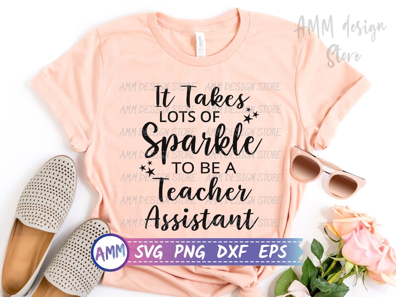 May include: A peach-coloured t-shirt with the text "It Takes Lots of Sparkle to Be a Teacher Assistant" in black. The text is surrounded by small stars. The shirt is laid flat on a white surface with a pair of shoes, sunglasses, and pink roses.