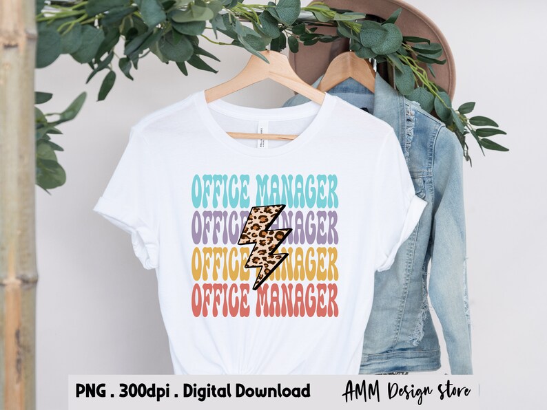 Pode incluir: Uma camiseta branca com o texto "OFFICE MANAGER" repetido quatro vezes em um esquema de cores arco-&iacute;ris. Um gr&aacute;fico de raio com estampa de leopardo est&aacute; centralizado entre o texto.