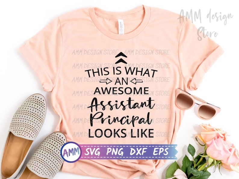 May include: A pink t-shirt with black text that reads "This is what an awesome Assistant Principal looks like". The text is surrounded by a repeating pattern of "AMM Design Store".