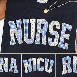May include: Navy blue sweatshirt featuring the word "NURSE" in appliqued blue and white floral and gingham patterns. Additional images show "CNA", "NICU", and "RN" in the same style. A gold necklace and a brown hat are also visible.