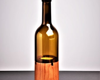May include: A decorative candle holder made from a repurposed brown glass bottle. The bottom section is crafted from light-colored wood. The candle holder is designed to hold a single candle, creating a warm, inviting ambiance. The overall design is simple and elegant.