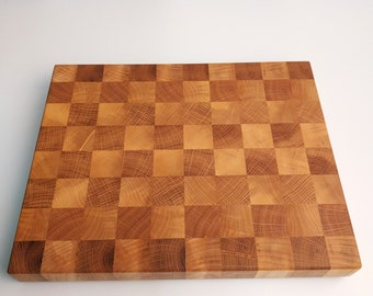 May include: A large, rectangular wooden cutting board with a checkered pattern. The board is made of light brown wood and has a natural finish.