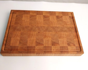 May include: A large, rectangular wooden cutting board with a checkered pattern. The board is made of light brown wood and has a natural finish.