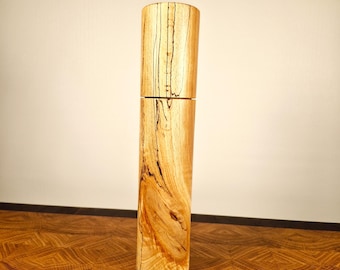 Könnte beinhalten: Eine Pfeffermühle aus Holz mit natürlicher Holzmaserung. Die Mühle steht auf einer Holzoberfläche mit Pfefferkörnern, die um sie herum verstreut sind.