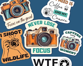 May include: A set of six colorful stickers featuring vintage cameras and photography-themed sayings. The stickers include phrases like "Focus on the good", "Never Lose Focus", "I Shoot Wildlife", "All I Need is Coffee and My Camera", "Capture Every Moment", and "WTF What's the f/stop".