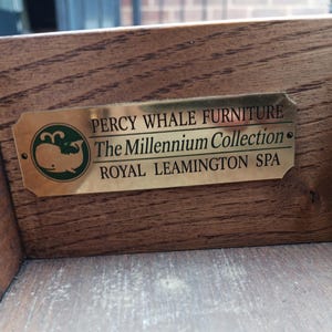 May include: A gold metal plaque with the text "Percy Whale Furniture The Millennium Collection Royal Leamington Spa" and a green whale logo.