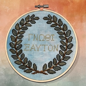 May include: A blue and white embroidery hoop with a wreath of brown leaves and the text "Timothy Layton" in gold thread.