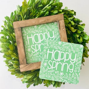 Peut inclure: Deux pancartes vertes avec des motifs floraux blancs et le texte "Happy Spring" en lettres blanches.