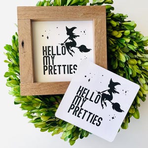 May include: A black and white sign with a witch flying on a broomstick and the text "Hello My Pretties".