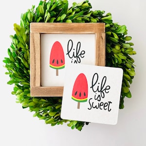 May include: A wooden sign with a watermelon popsicle graphic and the text "life is sweet".
