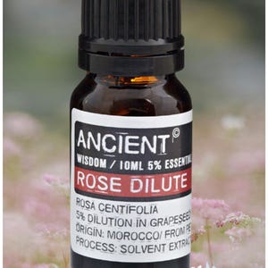 Könnte beinhalten: Kleine braune Glasflasche mit schwarzem Verschluss. Das Etikett lautet "ANCIENT ROSE DILUTE" mit Details zum ätherischen Öl, einschließlich Herkunft und Verfahren. Die Flasche enthält 10 ml Rosen-Ätherisches Öl.