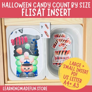 May include: A Halloween-themed counting activity for children featuring a gnome holding a pumpkin bucket. The activity includes a wooden tray with a removable insert, a printed card with a gnome, and a separate card with numbers 7 and 2. The tray also includes a small plastic container with candy pieces. The text on the cards reads "Halloween Candy Count by Size" and "Flisat Insert".
