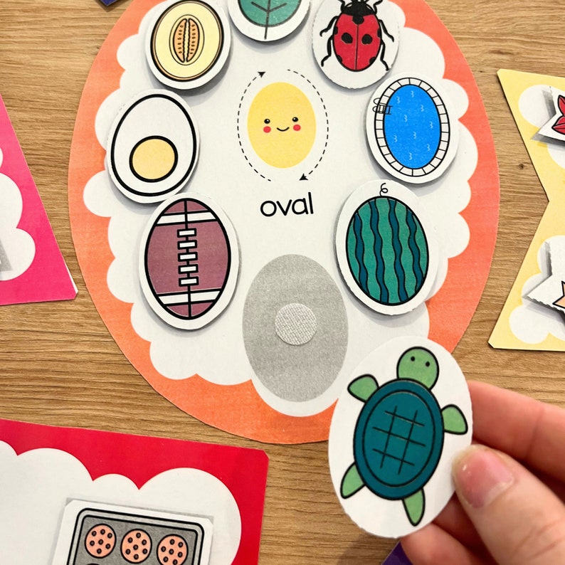 May include: A set of colorful felt shapes with different outlines, including a watermelon, a football, an egg, a ladybug, a sun, a melon, a leaf, a pool, and a turtle. The shapes are labeled "oval" and are designed for children's learning.