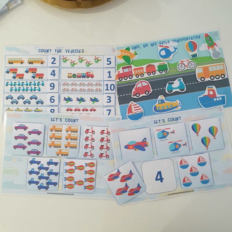 May include: A set of colorful educational flashcards for kids featuring different types of vehicles. The cards have images of cars, trucks, airplanes, helicopters, boats, and bicycles. Each card has a number on it, and the child can count the number of vehicles on each card. The cards are a fun and engaging way for kids to learn about different types of transportation and to practice their counting skills.