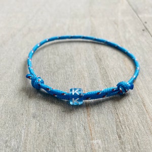 Pulseira Tau com letra azul água