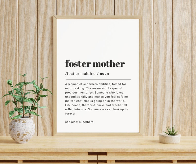 Puede incluir: Una definici&oacute;n imprimible en blanco y negro de la palabra "madre de acogida" con la pronunciaci&oacute;n y una descripci&oacute;n de la palabra. La definici&oacute;n est&aacute; enmarcada y colgada en una pared de madera.
