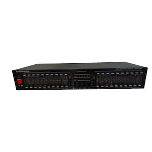 Può includere: Equalizzatore grafico AudioSource EQ-Seven nero con più controlli a cursore e un pulsante di accensione. L'unità ha una serie di cursori per la regolazione delle frequenze audio e un pannello di visualizzazione. Il nome del modello è stampato in alto a destra.
